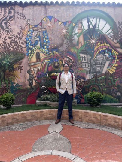 A man stands in front of a colorful mural, showcasing vibrant artwork and intricate designs.